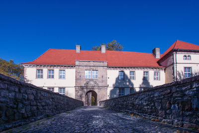 Street amidst buildings against clear blue sky, schloss strünkede