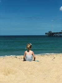 Full length of woman sitting on beach against sea