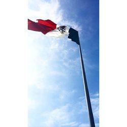 Low angle view of flags against cloudy sky