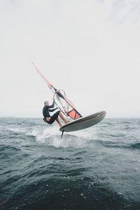 Man windsurfing in sea against sky