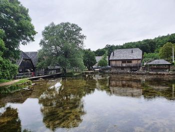 Reflection of trees and building in lake against sky