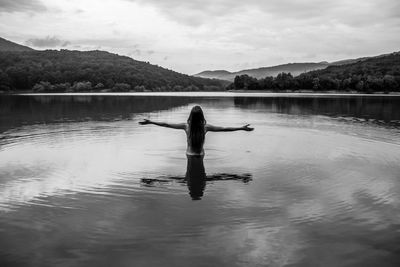 Rear view of person in lake against sky