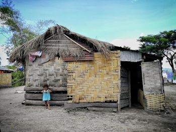 Boy standing by house against sky