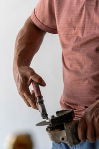 Man using angle grinder, cutting a screw, friction sparks, clamping screw with tweezers concentratio