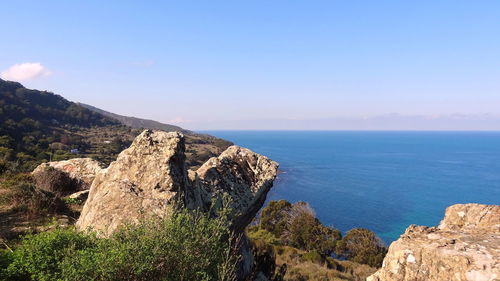 Scenic view of sea by mountains against sky