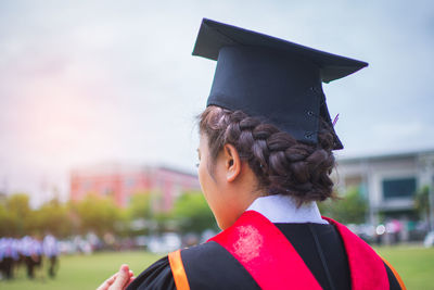 Rear view of woman wearing mortarboard against sky