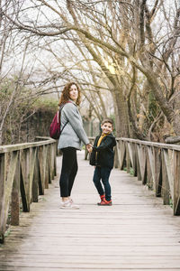 Portrait of mother with son standing on footbridge