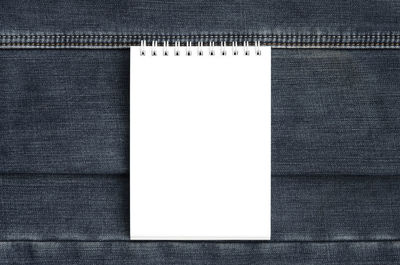 Directly above shot of spiral notebook on jeans