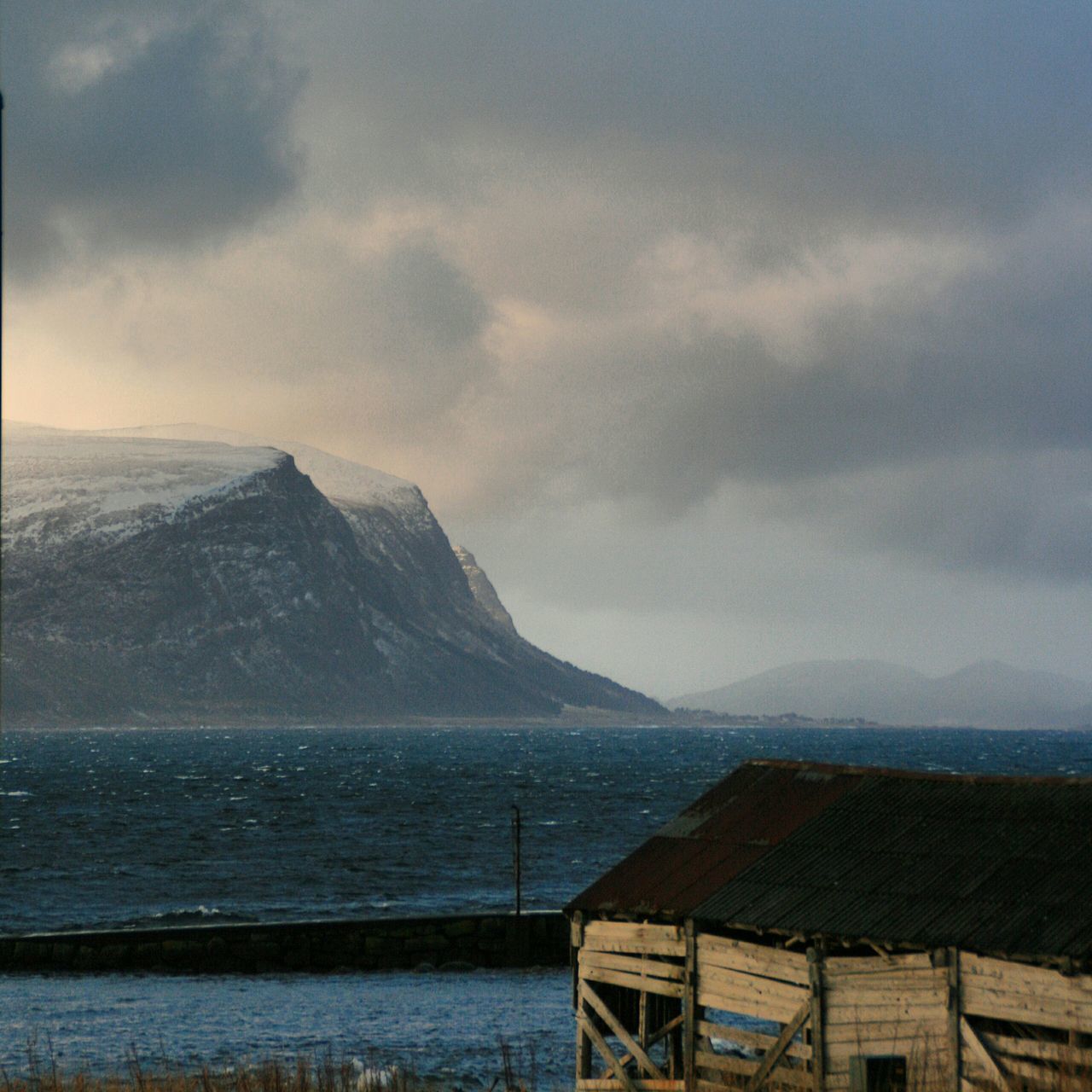 mountain, sky, cloud - sky, water, sea, scenics, mountain range, weather, cloudy, beauty in nature, tranquil scene, nature, tranquility, winter, built structure, cold temperature, building exterior, snow, architecture, cloud