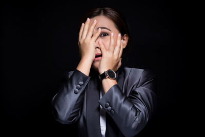 Portrait of scared businesswoman against black background