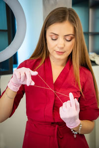 Woman holding thread while standing in beauty salon