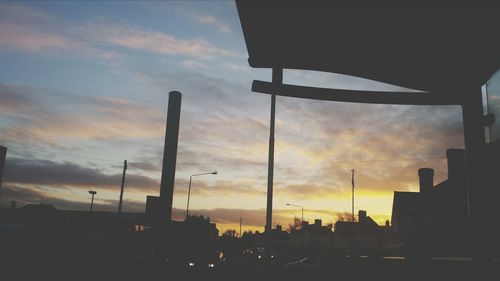 Silhouette of buildings against cloudy sky at sunset