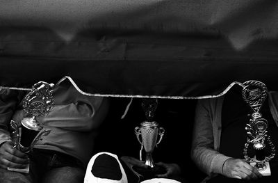 Midsection of people with awards sitting by curtain