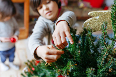 Close up on hands of child who is putting decoration on christmas tree