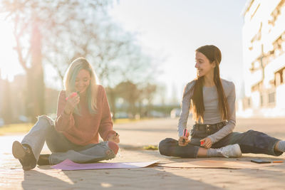 Smiling females writing on banner while sitting on street