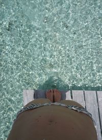 Low section of woman standing by swimming pool