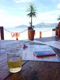 Close-up of drink on table at beach against sky