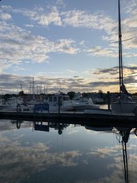 Sailboats moored at harbor against sky during sunset