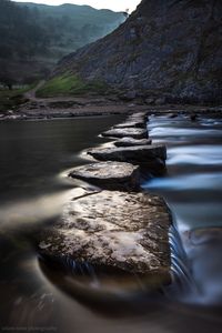 Surface level of rocks by river against sky
