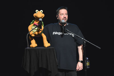 Full length of man holding toy while standing against black background