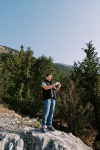 Side view of man standing on rock against clear sky