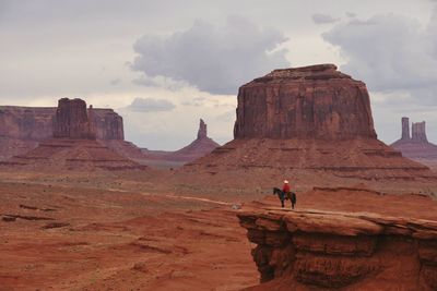 View of man on rock against cloudy sky