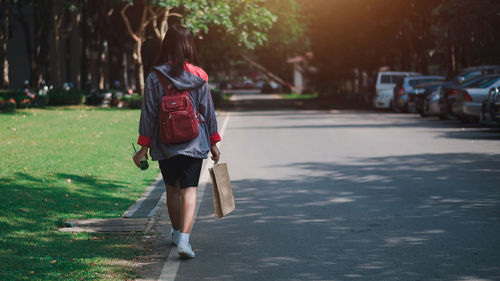 Rear view of woman walking on road in city