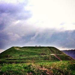 Scenic view of grassy field against cloudy sky