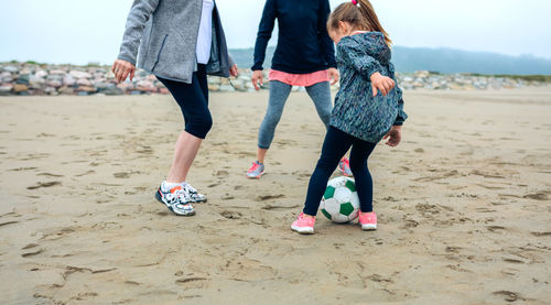 Woman with mother and daughter playing ball at beach