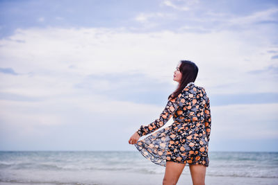 Midsection of woman standing at beach against sky