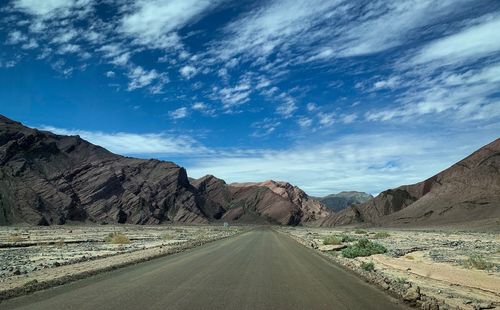 Road leading towards mountains against sky