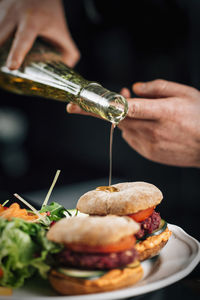 Chef pouring olive oil onto a vegan burger