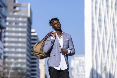 Man looking away standing against sky in city