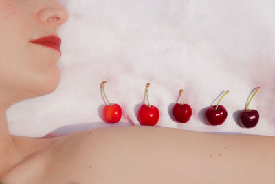 Close-up of woman with red cherries on bed