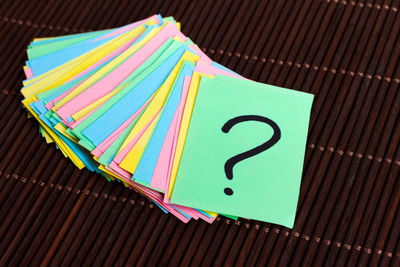 Colorful question marks written reminders tickets on wooden background.