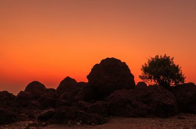 Silhouette rock formation against orange sky