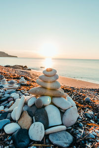 Stones on beach against sky during sunset