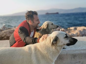 Smiling man with dogs against sea