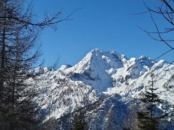 Low angle view of snowcapped mountains against clear blue sky