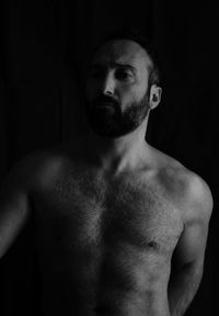 Portrait of shirtless man against black background