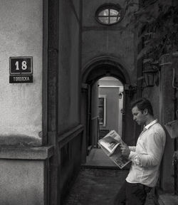 Side view of man standing by door of building