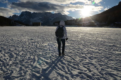 Rear view of woman standing on snow covered landscape