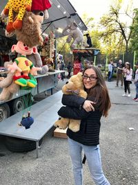 Happy young woman with toy standing against toys