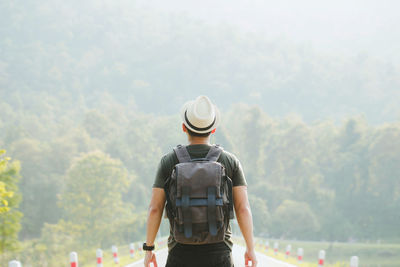 Rear view of man standing against trees