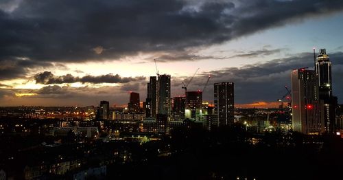 Illuminated buildings in city against sky during sunset