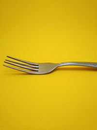 Close-up of fork against yellow background