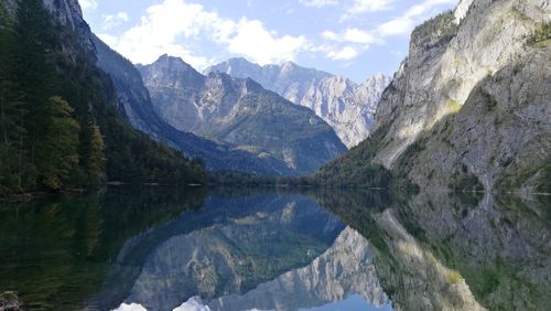 Wide scenic view of lake surrounded by mountain reflected in water