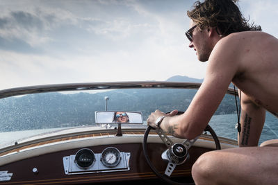 Man driving yacht against sky