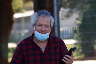 Portrait of man with mobile phone standing outdoors