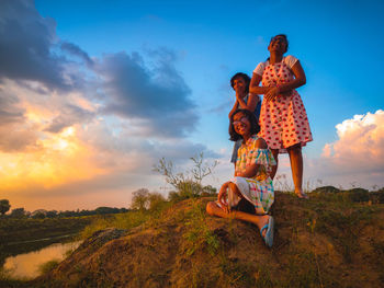 Rear view of people in traditional clothing against sky during sunset